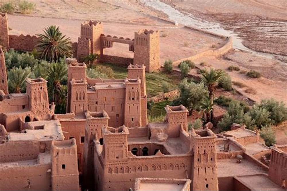Kasbah en pisé rouge d’Aït Benhaddou sous un ciel bleu, avec ses murailles et tours traditionnelles.